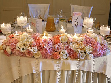 Pastelowe kwiaty w oprawie z koronki – dekoracja stołu pary młodej